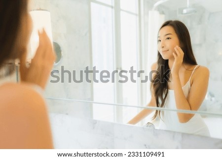 Portrait beautiful young asian woman check up and make up her face on mirror in bathroom interior