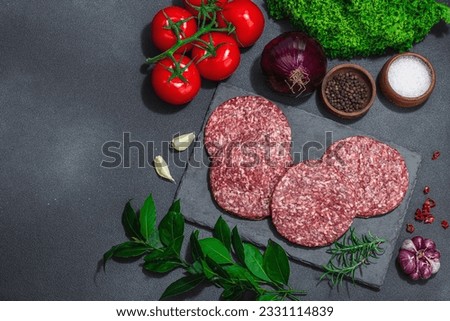 Raw burger patties. Fresh meat cutlets, spices, vegetables and herbs. Homemade American classic, traditional food for picnic, party or Independence Day. Dark stone concrete background, top view