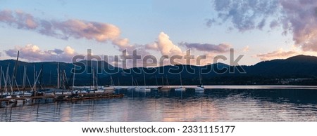 

Lake and yachts against the backdrop of a mountain landscape at sunset. Banner