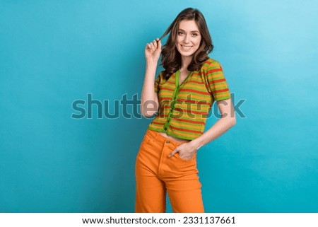 Photo of gorgeous adorable girl with curly hairstyle wear striped shirt touching curl arm in pocket isolated on blue color background