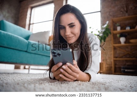 Photo of lady millennial blogger have free time lying cozy carpet communicate on apple iphone pro max in flat apartment