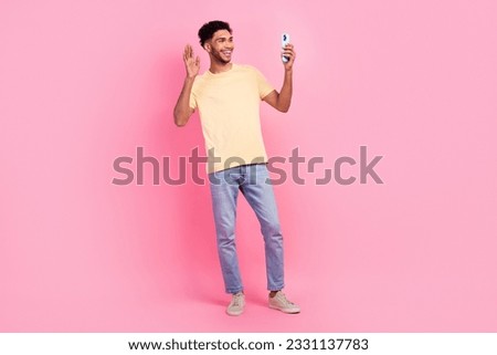 Full size photo of pleasant nice funny man wear yellow t-shirt talk on smartphone video call say hi isolated on pink color background