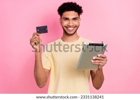 Photo of successful satisfied cool guy with earrings dressed yellow t-shirt hold tablet debit card isolated on pink color background