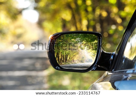 Reflection of  sunny autumn road at the car side mirrow. Royalty-Free Stock Photo #233114767