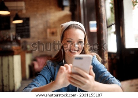 Young woman using a smart phone while sitting in an indoor cafe
