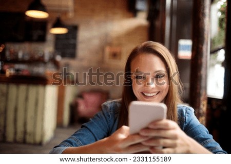 Young woman using a smart phone while sitting in an indoor cafe