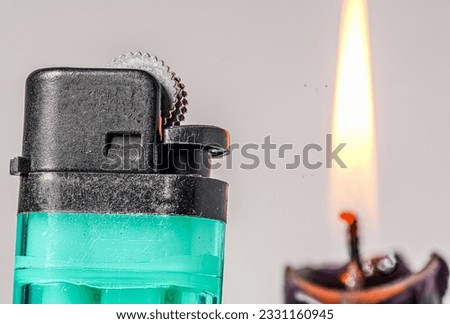 Lit black candle and lighter on a light gray background