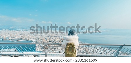 Woman tourist Visiting in Hakodate, Traveler in Sweater sightseeing view from Hakodate mountain with Snow in winter. landmark and popular for attractions in Hokkaido, Japan.Travel and Vacation concept Royalty-Free Stock Photo #2331161599