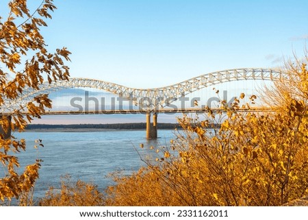 The tied-arch Hernando de Soto Bridge carrying Interstate 40 across the Mississippi River between West Memphis, Arkansas, and Memphis, Tennessee as seen from Mud Island Park on sunset with fall colors Royalty-Free Stock Photo #2331162011