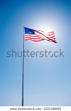 American flag blowing in clear blue sky.
