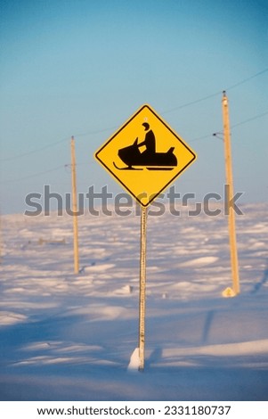 Snowy landscape with snowmobile crossing sign.