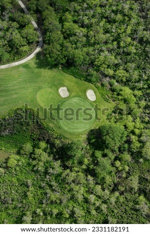 Aerial view of golf hole on golf course surrounded by trees in Maui, Hawaii.