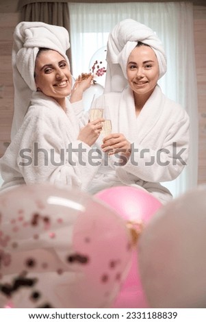 Cheerful young ladies in white bathrobes celebrating bachelorette party