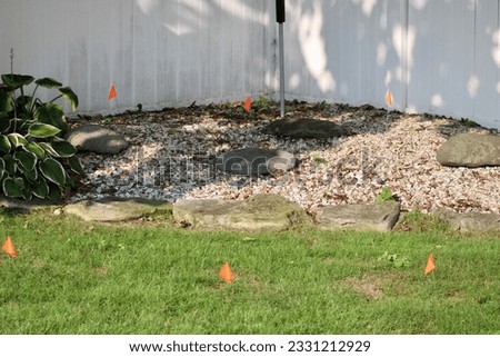 Orange flags that have been stuck into the ground on a construction site. They are used to mark underground utilities.
