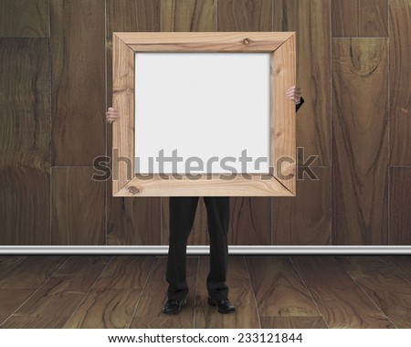 businessman holding blank whiteboard with wood frame on wooden room background
