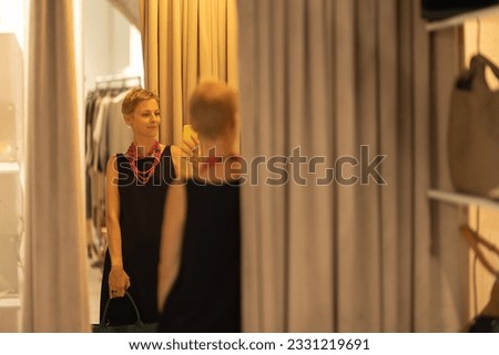 Adult stylish woman fashion consultant taking a picture of herself in the mirror of the boutique