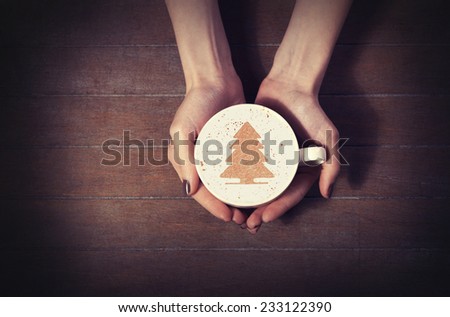 woman holding hot cup of coffee, with christmas tree shape