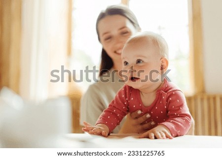 Cute nanny takes care of adorable child in kindergarten, holding her, smiling. Selective focus on baby. Toddler care concept Royalty-Free Stock Photo #2331225765