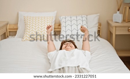 Middle age woman smiling confident lying on bed stretching arms at bedroom