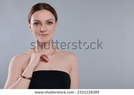Beautiful woman with elegant jewelry on light grey background. Space for text