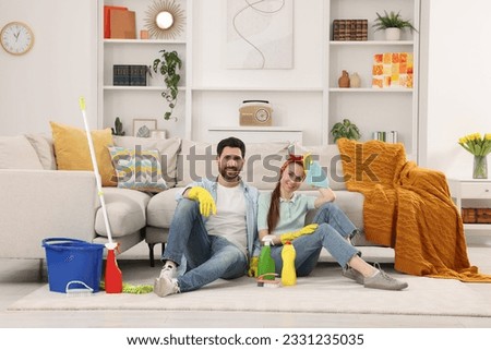 Spring cleaning. Couple with detergents and mop in living room Royalty-Free Stock Photo #2331235035