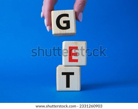 GET symbol. Concept word GET on wooden cubes. Businessman hand. Beautiful blue background. Business and GET concept. Copy space.