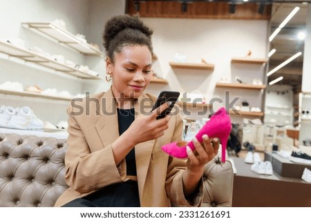 An African-American woman photographs a selected pair of shoes to show to a friend