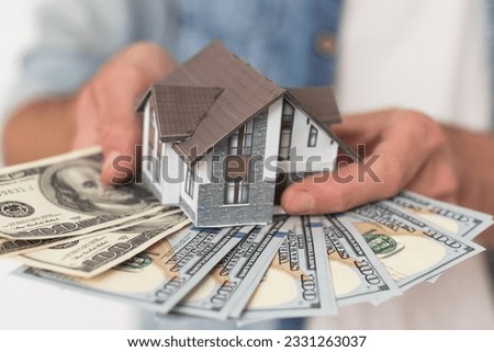 Real estate price and construction concept. Girl weighs money and a toy house in her hands