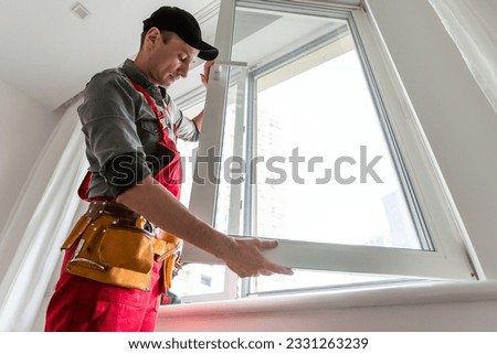 Cheerful young man mounting a kitchen window Royalty-Free Stock Photo #2331263239