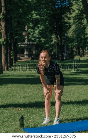 young sportswoman girl doing physical exercises on a sports mat yoga training outdoors in the park on grass healthy lifestyle concept