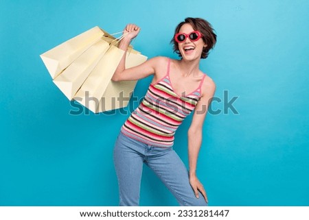 Photo of funky charming woman dressed tank top dark eyewear rising shoppers isolated blue color background