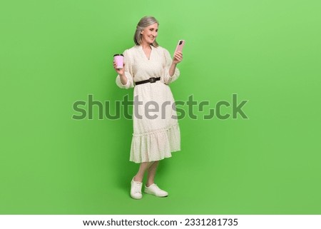 Full length photo of pretty sweet lady wear beige dress drinking beverage chatting instagram twitter telegram isolated green color background