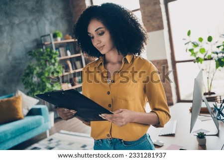 Photo of positive smart lady specialist dressed shirt smiling reading document before signing indoors workstation workshop