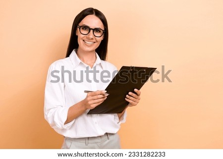 Photo of smiling charming lady wear white shirt spectacles writing documents empty space isolated beige color background Royalty-Free Stock Photo #2331282233
