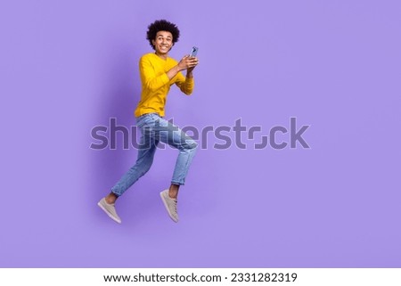 Full body size photo of funky positive young guy running fast speed use gadget texting online sms isolated over violet color background