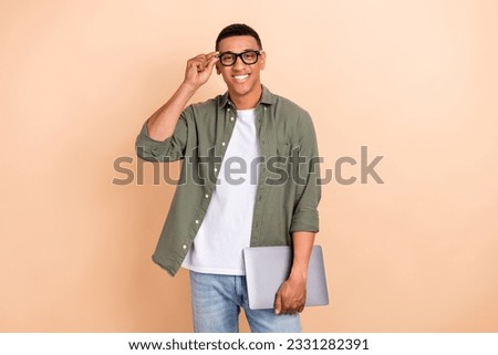 Photo of satisfied smart cheerful positive guy dressed khaki shirt touching glasses holding laptop isolated on pastel color background