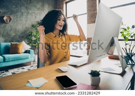 Photo of pretty lucky lady leader wear shirt rising fists reading increase report modern gadget indoors workplace workstation