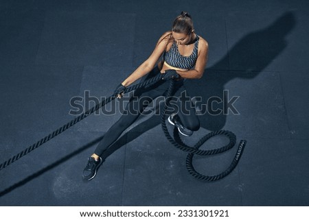 Power sporty female athlete exercising with rope at a gym top view. Royalty-Free Stock Photo #2331301921