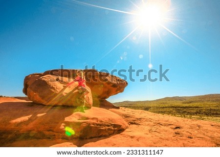 Tourist woman after trekking atop of Kalaranga Lookout with spectacular views of sandstone amphitheatre. Sunrays in blue sky. Finke Gorge National Park, Northern Territory, Central Australia Outback. Royalty-Free Stock Photo #2331311147