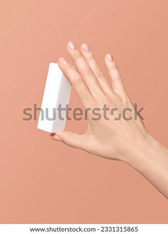 A closeup of nail care and nail treatment procedure at home or beauty salon. Beautiful female hands with minimal nail polish, holding a nail buffer file creating self-made or hygiene manicure. Royalty-Free Stock Photo #2331315865