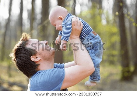 Proud father playing with his newborn son during walking in the park. Happy middle age man tossing his little baby in the air. Parenthood. Involved dad taking care of his infant son Royalty-Free Stock Photo #2331330737