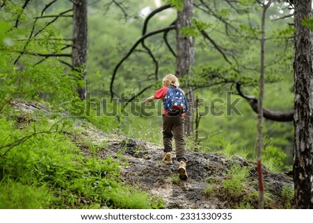 School child is hiking and exploring nature in forest. Preteen boy travel in woodland. Summer vacation activity for inquisitive kids in parkland. Adventure, tourism, scouting, orienteering for kids Royalty-Free Stock Photo #2331330935