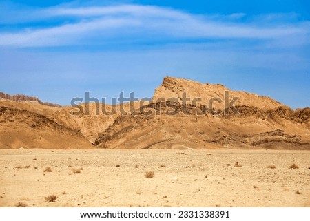 Landscape photography of Sahara desert, sand dunes and stones sunny day. View of expanses of desert hills with sand, vegetation and blue sky, Sahara, Tozeur city, Tunisia, Africa. Copy ad text space Royalty-Free Stock Photo #2331338391