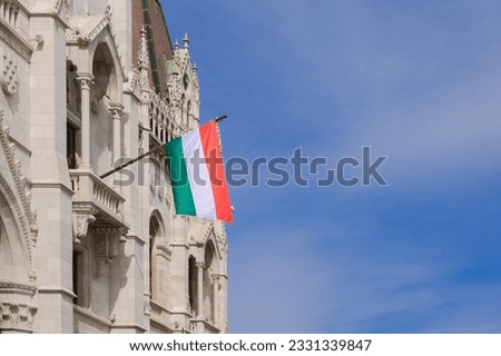National Hungarian flag on wall of Parliament building and blue sky background