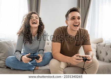 Two people couple man and woman boyfriend and girlfriend husband and wife or friends play console video games hold joystick controller happy smile emotional gesture reaction family leisure copy space