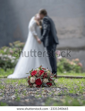 Wedding bouquet on foreground of a blurred kissing couple. Flowers and lovers