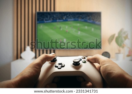Video game controller, gaming concept with TV screen in background Royalty-Free Stock Photo #2331341731