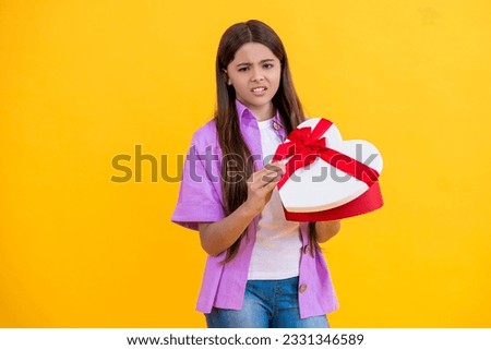teen girl hold heart box for Valentines Day. teen girl has Valentines mood. teen girl hold gift on Valentines Day. teen girl holding box of chocolates. be my valentine. displeased about the present