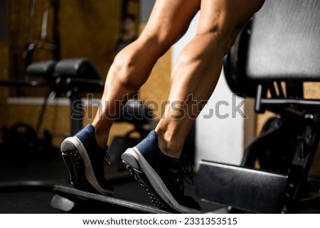 An unrecognizable bodybuilder is working the twins or gastrocnemius on a machine inside a gym. Concept of working legs, strong calves, lifting weight with gastrocnemius. Royalty-Free Stock Photo #2331353515