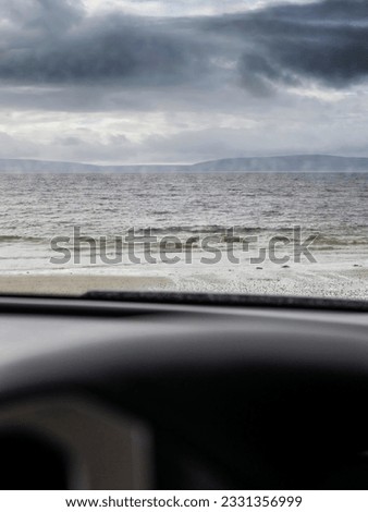 View from a car on a beautiful seascape with ocean and mountain in the background. Galway bay, Ireland. Dark and dramatic sky. Travel and sightseeing concept.